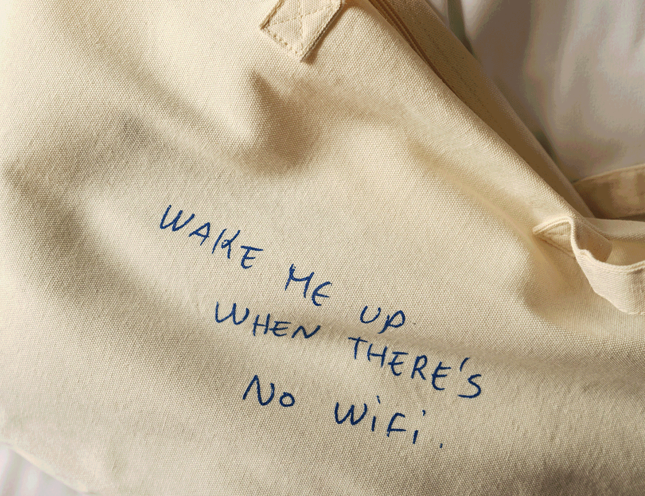 Una bolsa de lona beige con un mensaje escrito a mano con tinta azul que dice: 