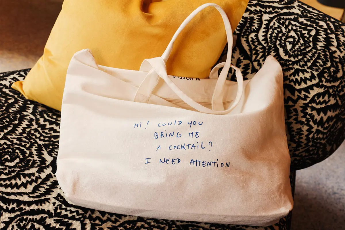 Una bolsa de lona blanca con un texto azul que dice: 