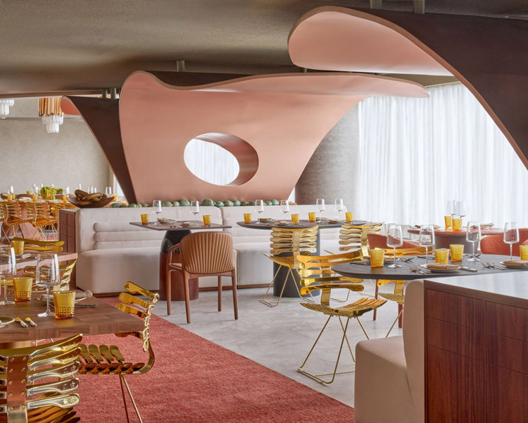 Ein modernes Restaurant mit skulpturalen rosa Tafeln, goldfarbenen Stühlen, Holztischen und gelben Gläsern. Große Fenster mit transparenten Vorhängen lassen natürliches Licht in den stilvollen, modernen Raum.