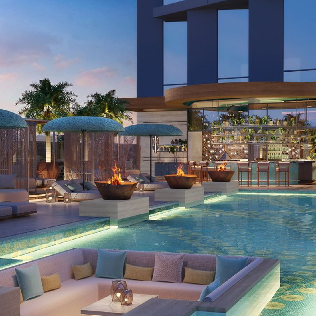 A modern rooftop pool area at sunset features fire pits, cabanas, sun loungers, a bar with stools, palm trees, and a sunken seating area with cushions by the water. The atmosphere is stylish and inviting.
